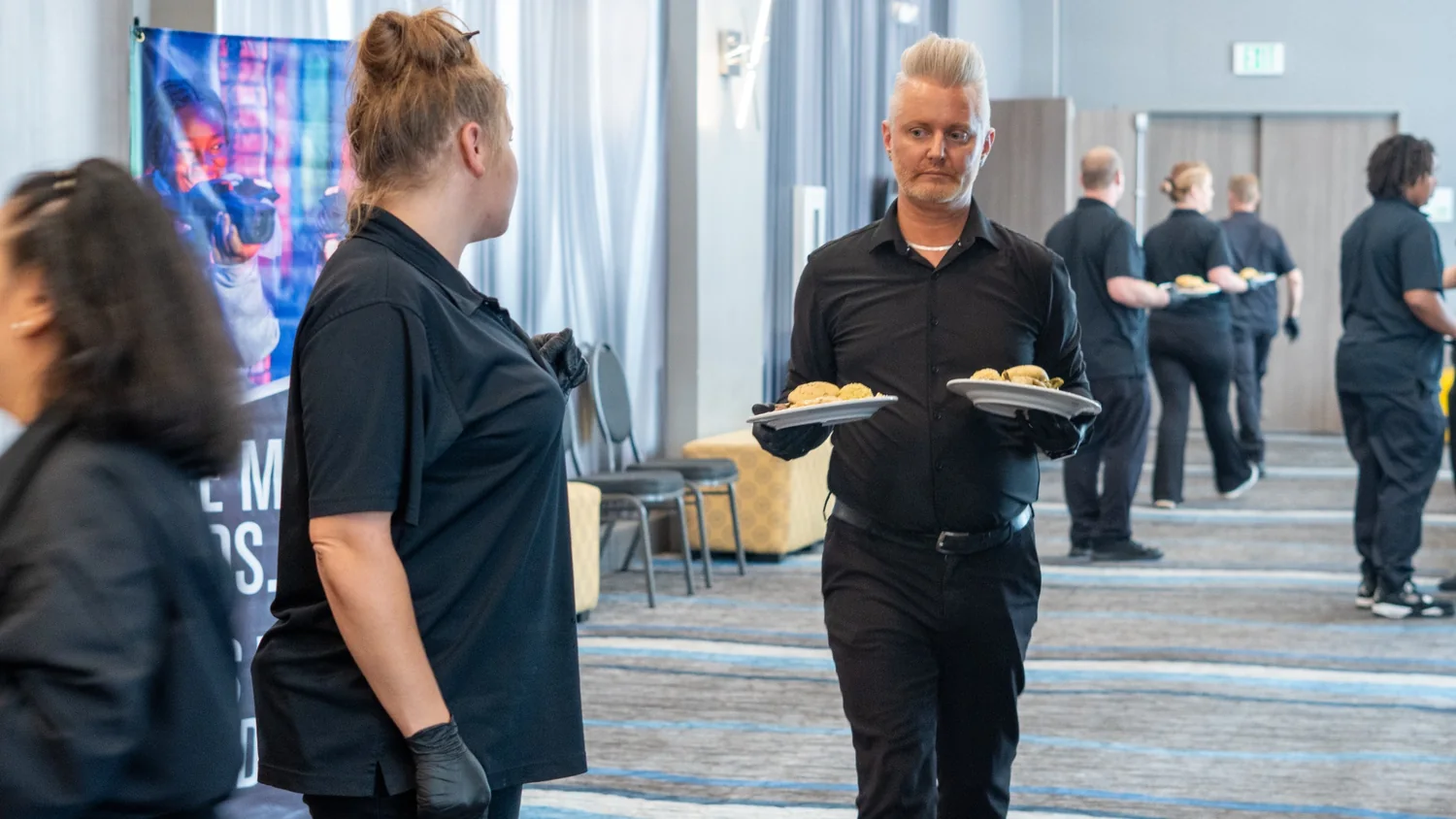 Event service staff carrying plated meals